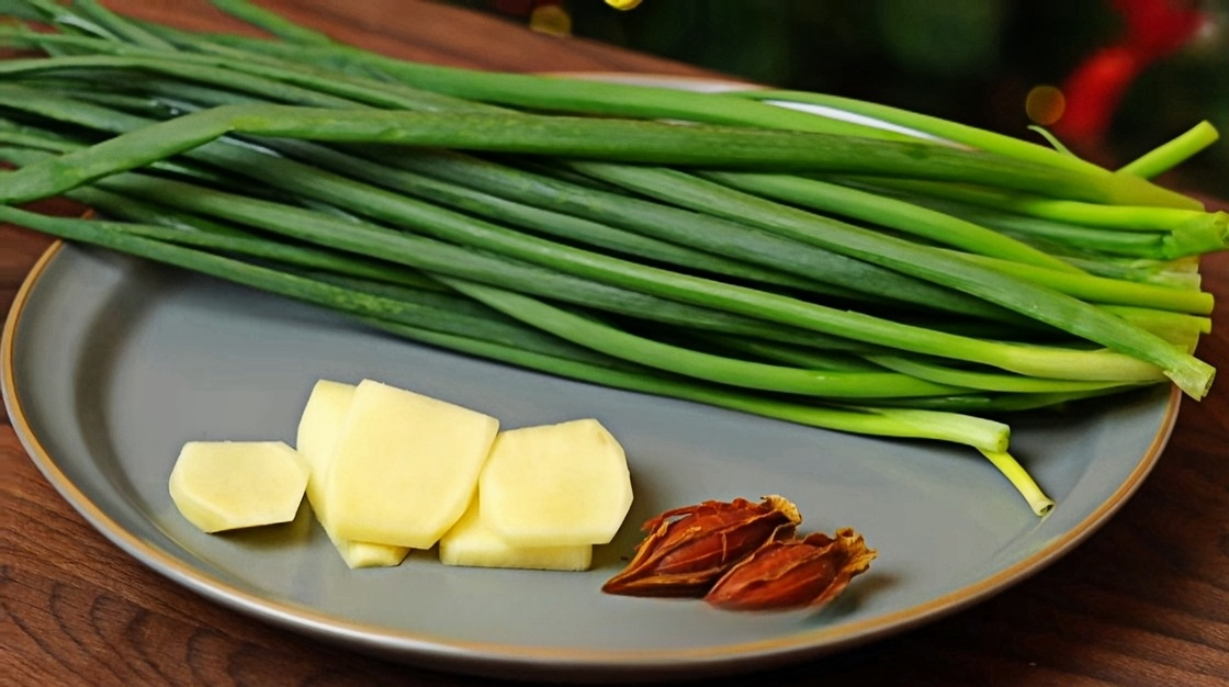 On the plate are green onions, ginger, and yellow gardenia fruit.